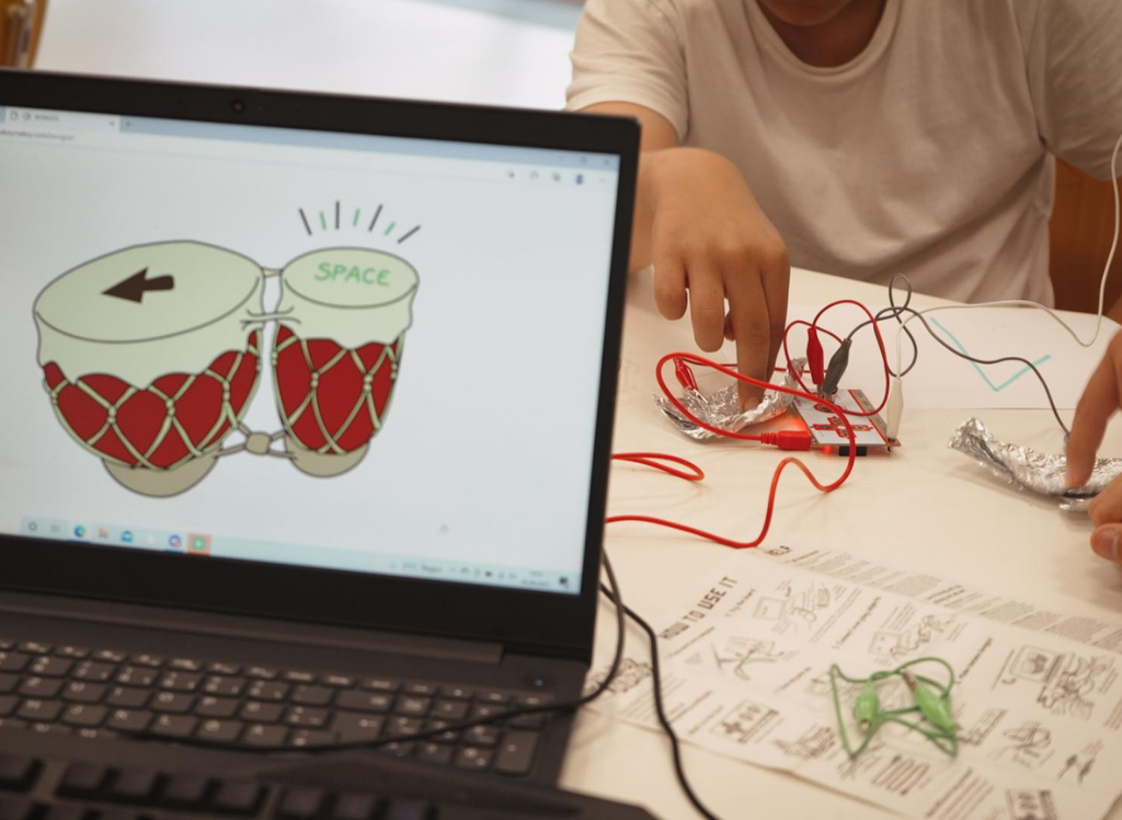 Laptop mit geöffnetem Progamm Makey Makey Bongos. Die Trommeln werden über den angeschlossenen Makey Makey-Controller gespielt.