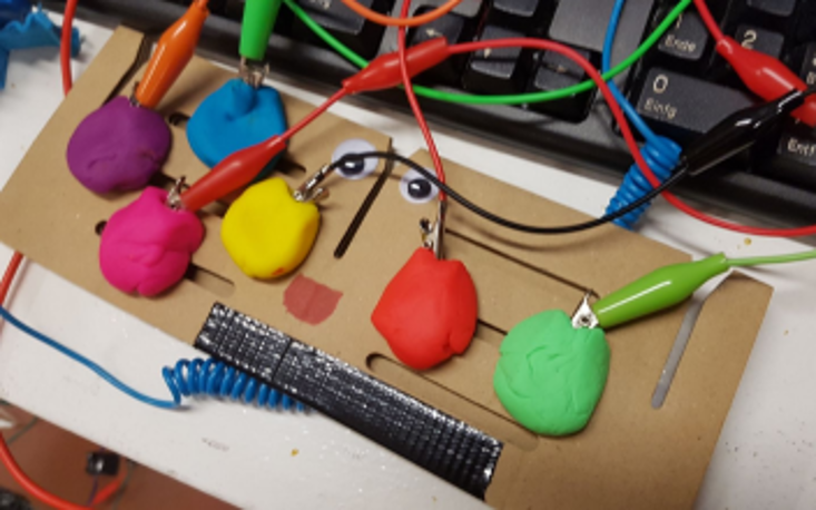 Selbst gebastelter Controller aus Knete mit der Makey-Makey-Platine, an der leitfähige Materialien angeschlossen werden können, um Tastaturfunktionen zu übernehmen.