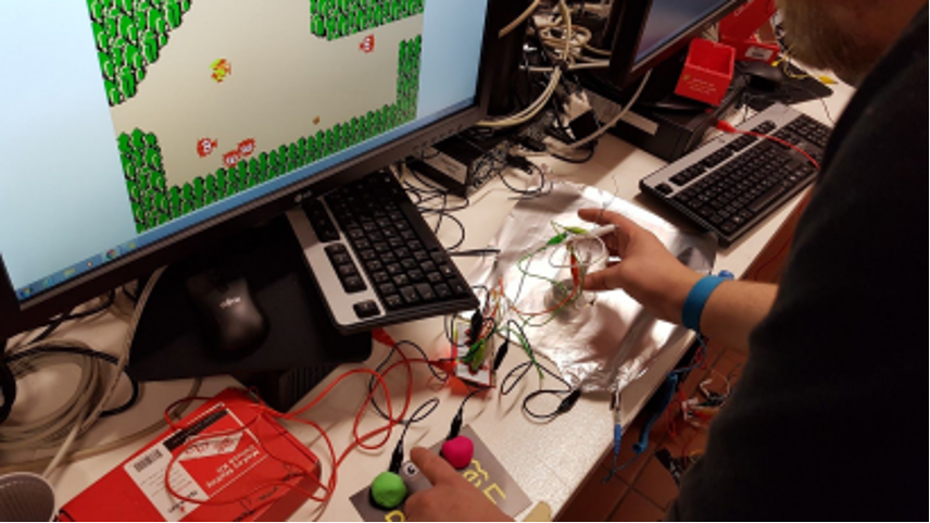 Ein Computerspielt wird einer selbstgebastelten Spielesteuerung gespielt, die aus Knete und einen Makey-Makey-Controller hergestellt wurde.
